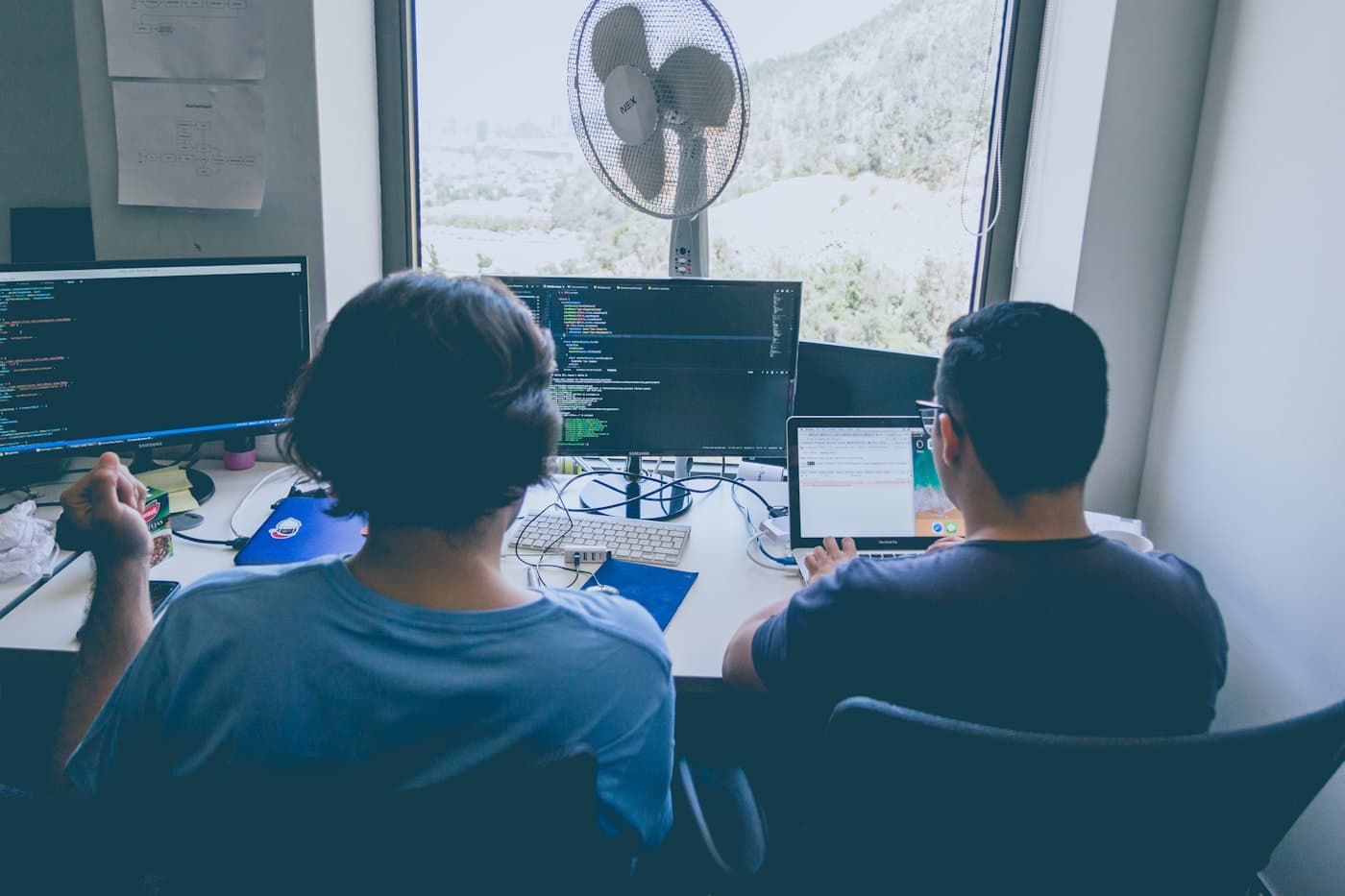 Deux professionnels travaillent devant des écrans de code